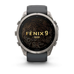 A Garmin Fenix 9 Pro smartwatch with a dark gray strap and a silver-toned metal case, shown from the front on a white background. The watch face displays a black background with gold topographic lines and the text 'FENIX 9 PRO'.