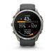A Garmin smartwatch with a round silver-tone metal case and a dark gray silicone strap, shown on a clean white background. The watch face is active with various fitness and heart rate metrics displayed.