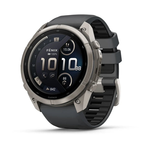 A rugged smartwatch with a round silver-tone metal case and a dark gray silicone strap, shown at a three-quarter angle on a white background. The watch face displays 'FENIX' and 'GARMIN' branding.