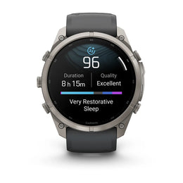 A Garmin smartwatch with a round silver-tone metal case and a dark gray strap, shown on a clean white background. The digital display is active, showing sleep and activity metrics.