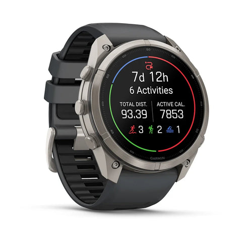 A Garmin smartwatch with a round silver-tone case and a dark gray silicone strap, shown on a clean white background. The watch face is illuminated with a black screen displaying fitness metrics.