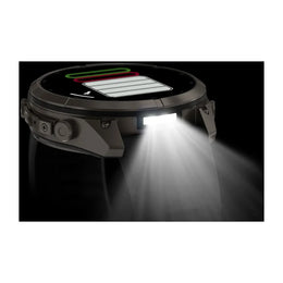 A rugged smartwatch shown at an angle with its front light turned on, emitting a bright beam of light downward against a black background.