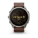 A Garmin Fenix 9 Pro smartwatch with a round silver-toned metal case and a brown leather strap, shown against a plain white background. The watch face displays a black background with gold topographic lines and the text 'FENIX 9 PRO'.