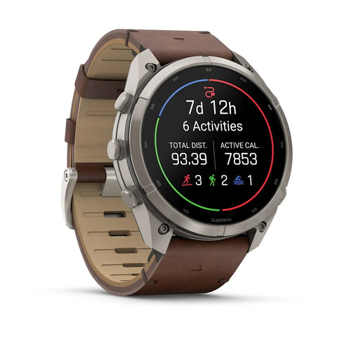 A Garmin smartwatch with a brown leather strap and a silver-toned metal case, shown at a three-quarter angle on a white background. The watch face displays fitness metrics.