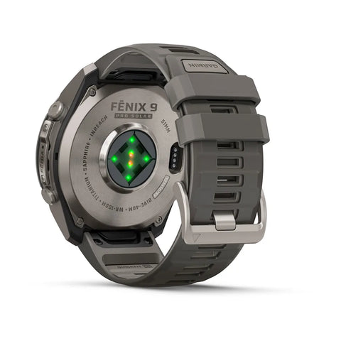 The back of a Fenix 9 G10 smartwatch with a dark gray silicone strap and metallic gray case, showing the heart rate sensor and green LED indicators, on a white background.