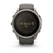 A Garmin Fenix 9 Pro smartwatch with a round silver-toned metal case, dark gray strap, and a black display showing a topographic map pattern with gold lettering.