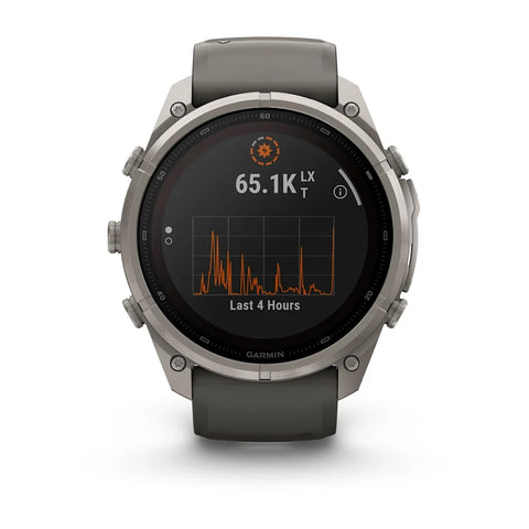 A Garmin smartwatch with a round silver titanium case and a dark gray silicone strap, shown on a clean white background. The watch face displays a black screen with an orange and white activity graph.