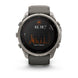 A Garmin smartwatch with a round silver titanium case and a dark gray silicone strap, shown on a clean white background. The watch face displays a black screen with an orange and white activity graph.