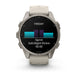 A Garmin smartwatch with a round silver-toned metal case and a light beige silicone strap, shown on a clean white background. The watch face is active with a black display showing a fitness graphic and the word 'FRIDAY'.