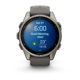 A Garmin smartwatch with a round metallic gray case and a dark gray silicone strap, shown on a clean white background. The watch face is illuminated with a blue digital display showing the time, weather, and a Polish greeting.