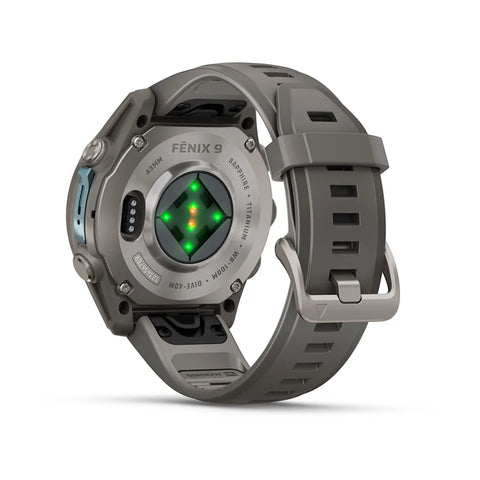 A rugged gray smartwatch shown from the back, featuring a textured gray strap, metallic gray case, and a central green and orange LED light display. The brand name 'FENIX 9' is visible on the back of the case.