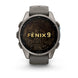 A Garmin Fenix 9 smartwatch with a round metallic gray case, a dark gray silicone strap, and a black watch face featuring a gold topographic map design and the text 'FENIX 9'.