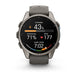 A Garmin smartwatch with a round dark gray titanium case and a matching dark gray silicone strap, shown against a plain white background. The watch face is active with various fitness and health metrics displayed.