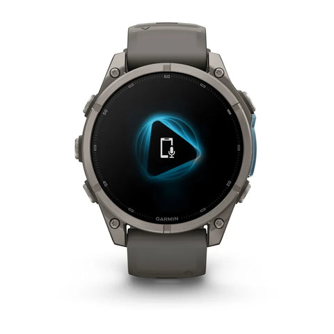 A Garmin smartwatch with a dark gray silicone strap and a metallic gray round case, shown against a plain white background. The watch face is black with a glowing blue geometric icon in the center.