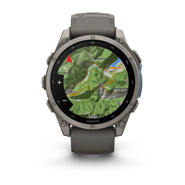 A Garmin smartwatch with a dark gray silicone strap and a metallic dark gray case, shown on a clean white background. The watch face is active with a green topographic map display.