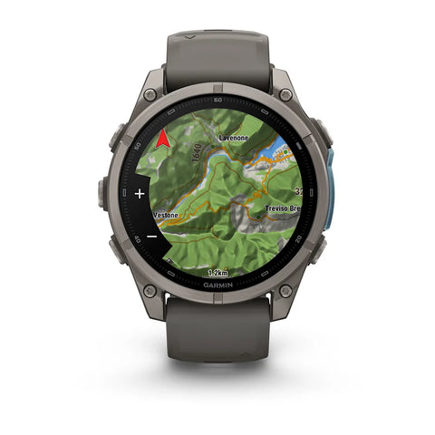 A Garmin smartwatch with a dark gray silicone strap and a metallic dark gray case, shown on a clean white background. The watch face is active with a green topographic map display.