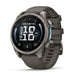 A Garmin Fenix smartwatch with a dark gray silicone strap and a metallic gray round case, shown at a three-quarter angle on a white background.