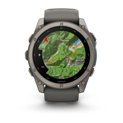 A Garmin smartwatch with a dark gray titanium case and matching silicone strap, shown on a clean white background. The watch face is illuminated with a green topographic map display.