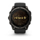 A Garmin Fenix 9 smartwatch with a black and dark gray rugged case, black strap, and a black watch face featuring gold topographic contour lines and the text 'FENIX 9' in gold. The watch is centered on a clean white background with a soft shadow underneat