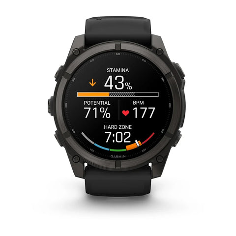 A black Garmin smartwatch with a round face and black strap, shown against a plain white background. The watch face is illuminated with a digital sports screen displaying fitness metrics.