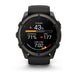 A black Garmin smartwatch with a round face and black strap, shown against a plain white background. The watch face is illuminated with a digital sports screen displaying fitness metrics.