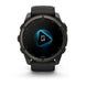 A black Garmin smartwatch with a round dark gray case and a black strap, shown from the front on a white background. The watch screen displays a blue and white audio interface.