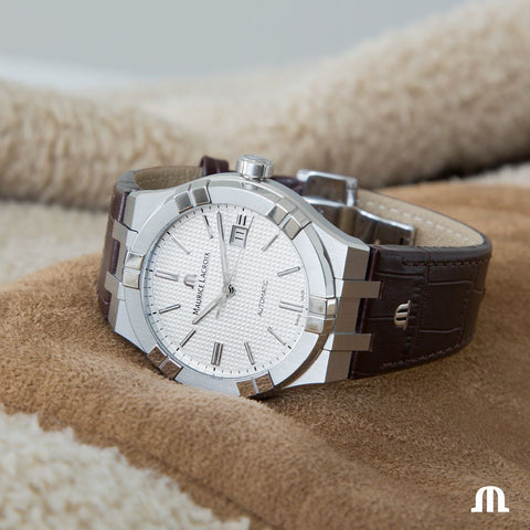 Silver watch with a brown leather strap on a textured surface