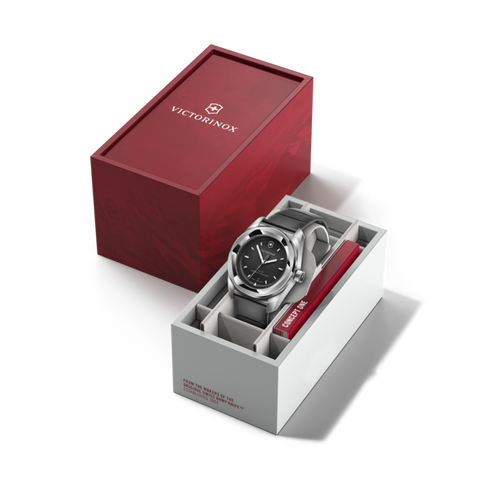Silver watch with blue face in a white box, next to a red Victorinox box on a black background