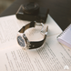 Watch on an open book with a camera in the background