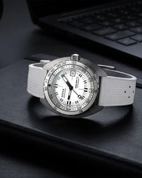 A wristwatch with a white textured strap, a silver-tone case, and a white dial with black markings, resting on a black surface with a blurred laptop keyboard in the background.