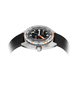 A close-up of a dial steel watch with a black bezel, black dial, orange accents, and a black textured strap, shown against a white background with a soft shadow.