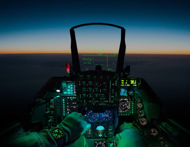 Pilot's view from inside a fighter jet cockpit during night flight.