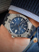 Close-up of a wrist wearing a silver watch with a blue face.