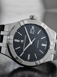 Maurice Lacroix watch with black dial and silver case on a blurred background