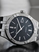 Maurice Lacroix watch with black dial and silver case on a blurred background
