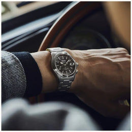 Person wearing a silver watch with a blurred car interior background