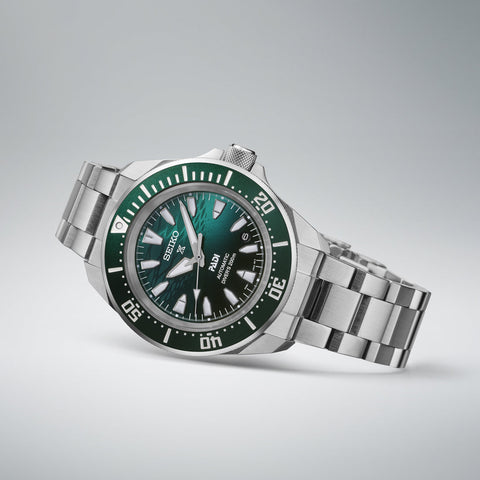 Seiko watch with green dial and silver bracelet on a light gray background