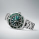 Seiko watch with green dial and silver bracelet on a light gray background